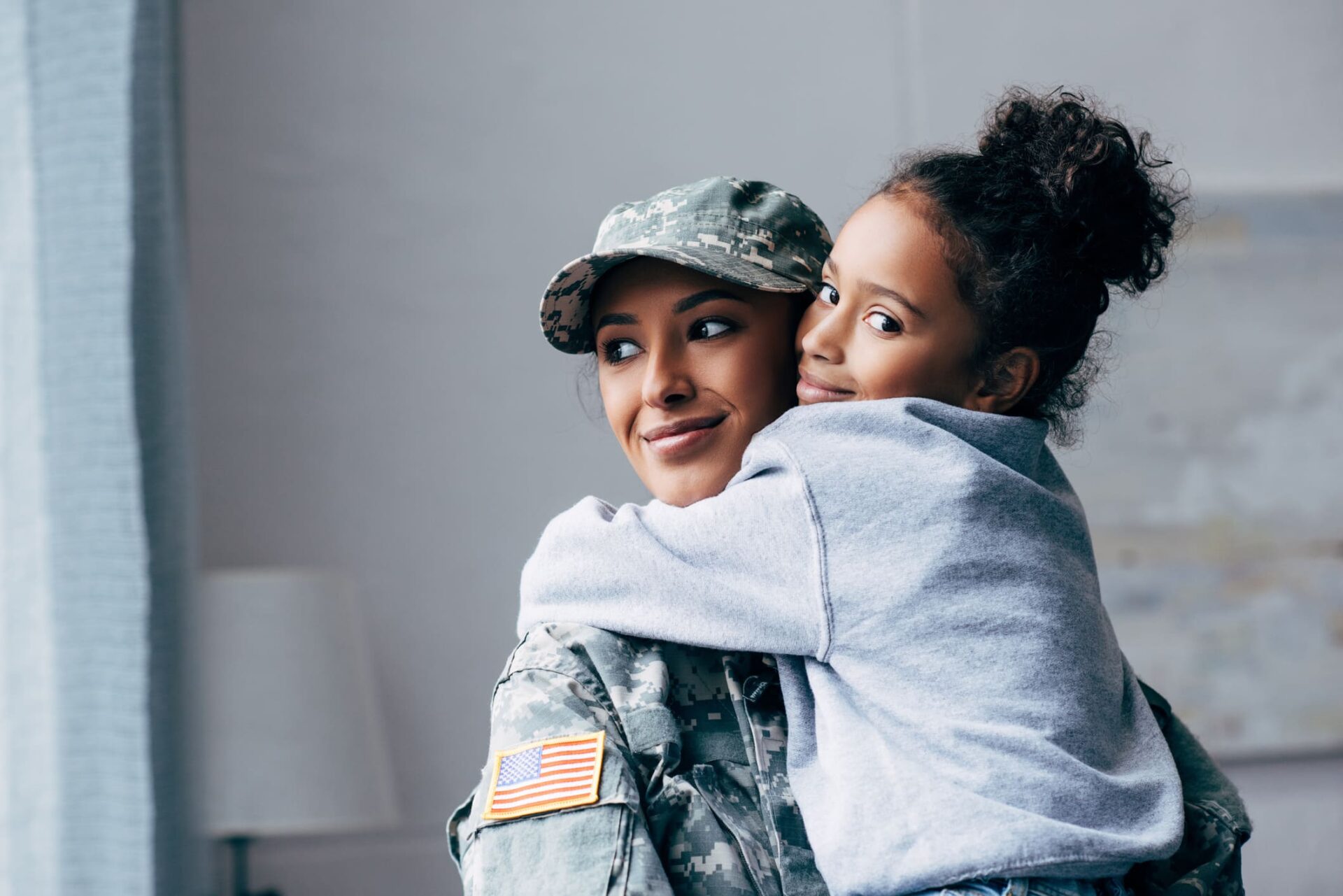 Madre con uniforme militar abrazando a su hija