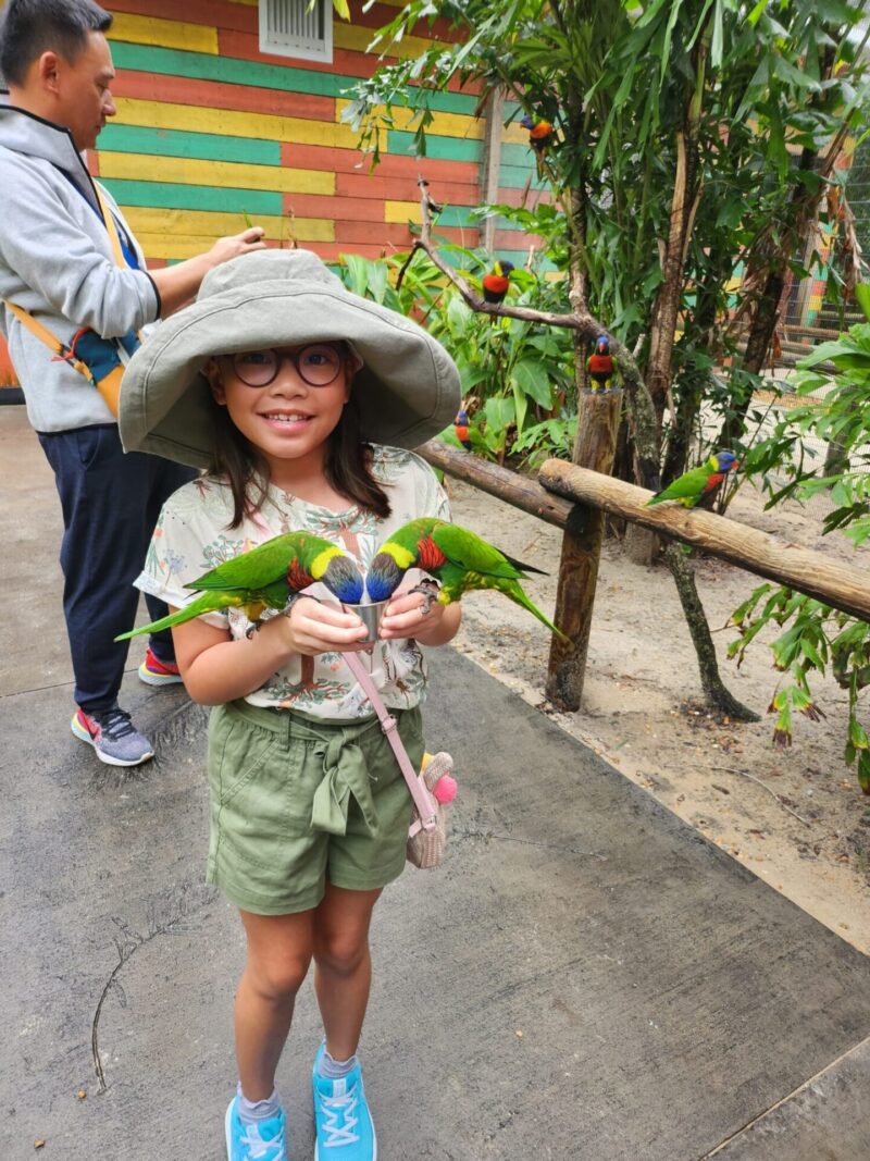 Niña con loros en las manos