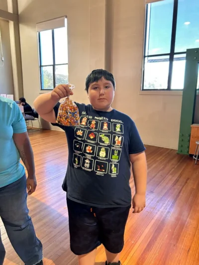 Un joven está de pie en el interior, sobre un suelo de madera.