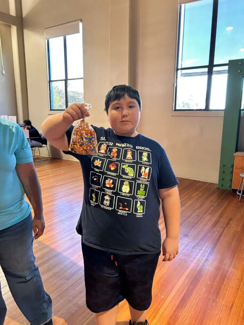 Un joven está de pie en el interior, sobre un suelo de madera.