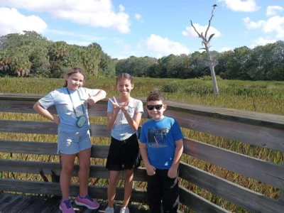 Tres niños pequeños de pie y sonriendo