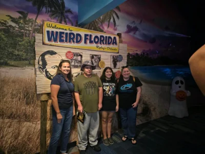 Un grupo de cuatro personas posa delante de un cartel de "Welcome to Weird Florida" en Ripley's Orlando.